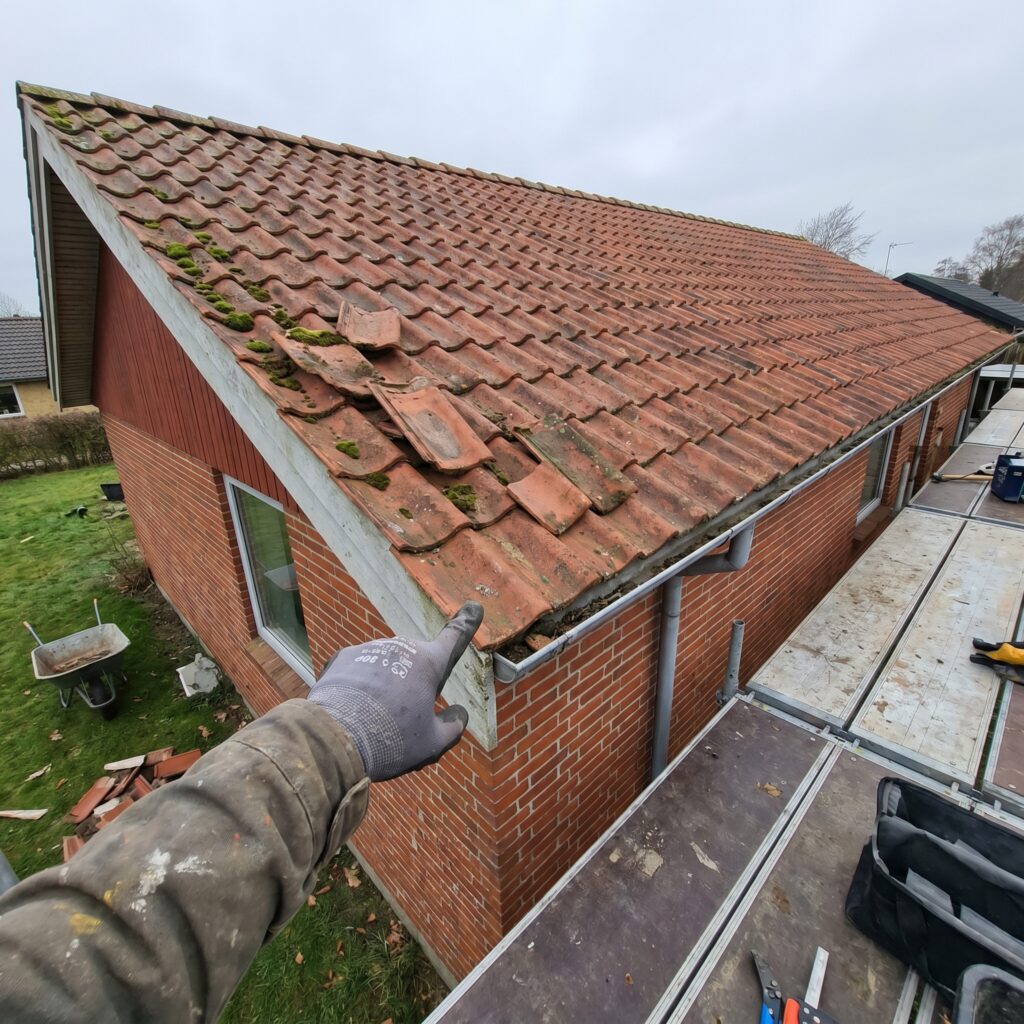 overlap-tag, roof_chimney, detail, outdoor, tag,skorsten,tagrender,inddækning,tagsten,rygning,vedligehold,reparation, Nærbillede af løse tagsten, mos og rygning der skal vurderes., på et lavt parcelhus hvor arbejdet kan ses fra haven., dansk bolig, håndværk, renovering, vedligeholdelse, pris, tilbud, roof_chimney, detail, outdoor, tag,skorsten,tagrender,inddækning,tagsten,rygning,vedligehold,reparation