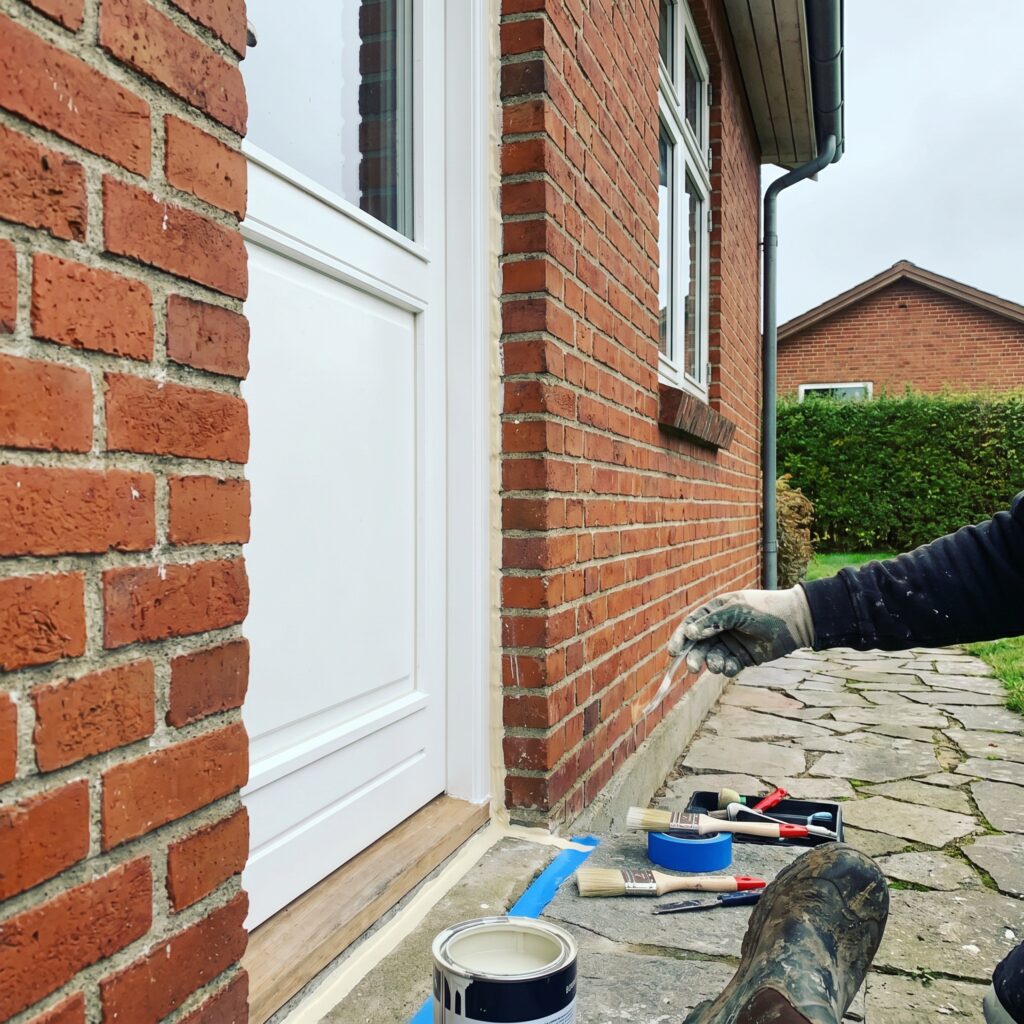 overlap-vinduer-doere, windows_doors, detail, mixed, vinduer,døre,glas,karme,fuger,fugebånd,tætning,udskiftning,vedligehold, Nærbillede af dørkarm med justeret fuge og malet træværk., på en rød murstensvilla., dansk bolig, håndværk, renovering, vedligeholdelse, pris, tilbud, windows_doors, detail, mixed, vinduer,døre,glas,karme,fuger,fugebånd,tætning,udskiftning,vedligehold